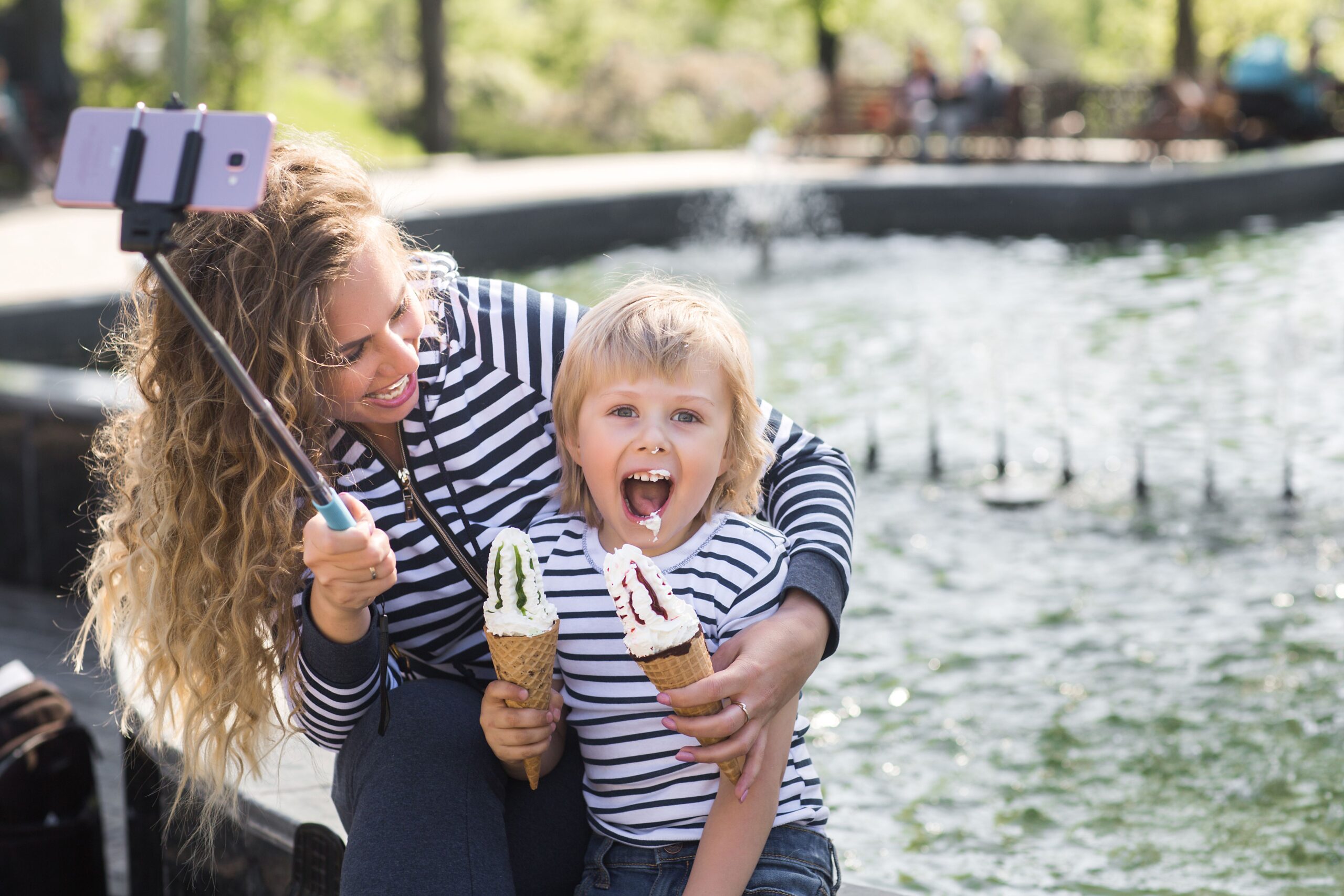 Kids_attraction_Cute_little_boy_and_his_mother_staining_each_other_with_ice_cream_near_the_fountain_outdoors_baeb463ff3